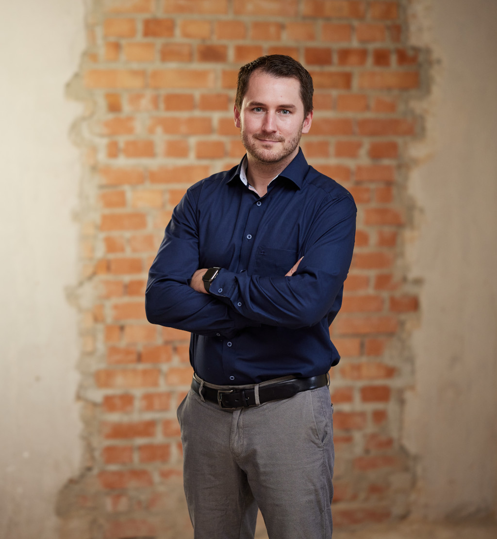 Modern business person in front of red brick wall, professional portrait, business, career, confidence.