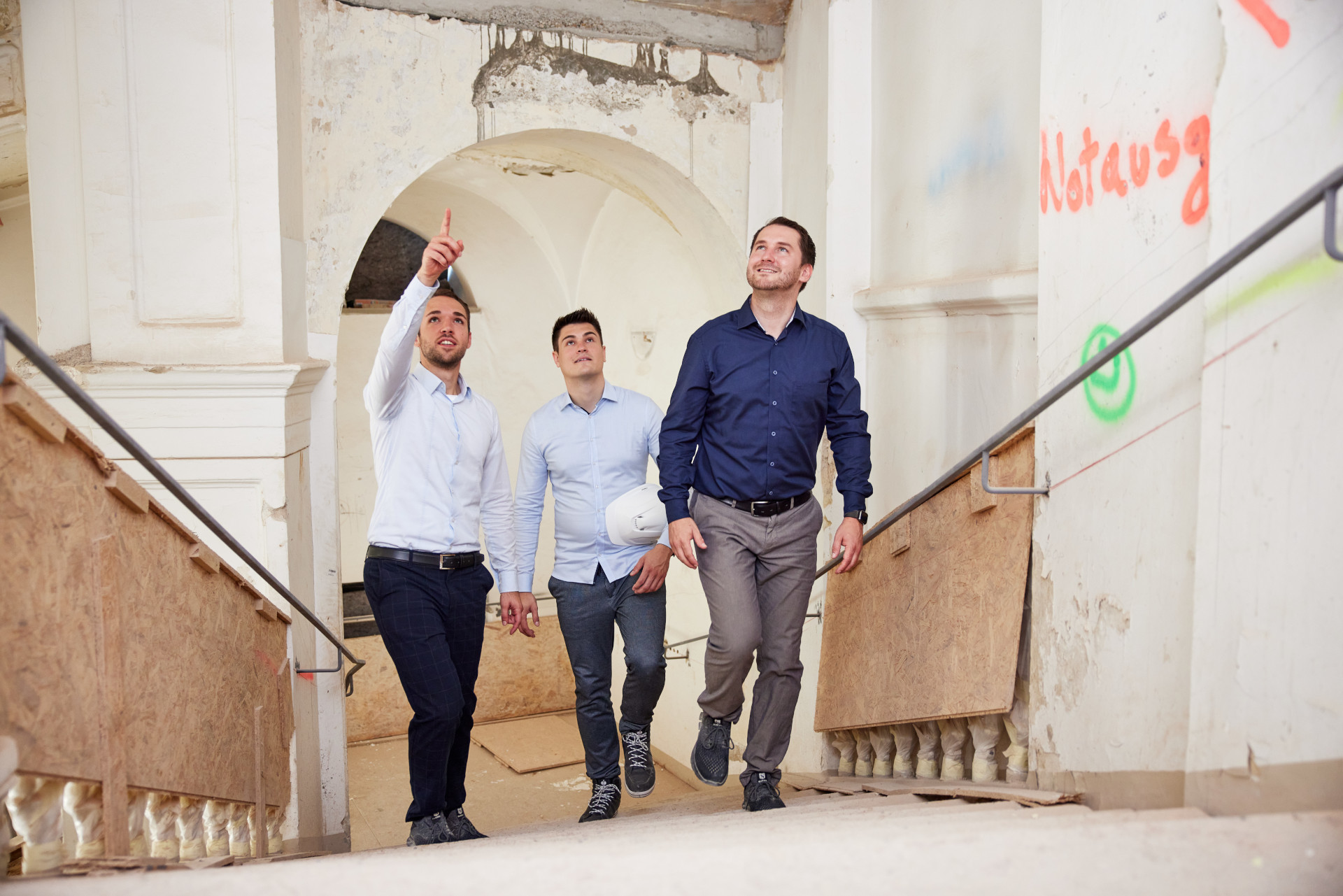 Three men are walking down a flight of stairs.