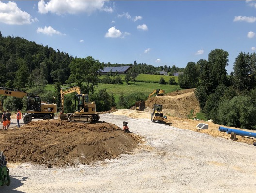 Baustelle mit Erdbewegung und Baumaschinen in ländlicher Umgebung, Fortschritt im Bauprojekt.